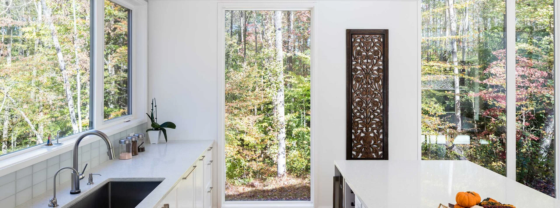 Bright kitchen with wide JELD-WEN windows looking toward a wooded landscape